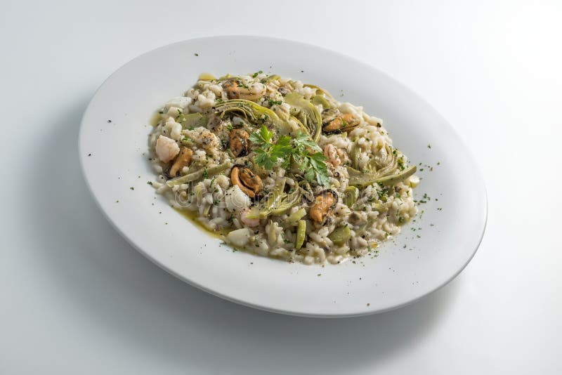 Round white dish of risotto with artichokes and seafood isolated on white background