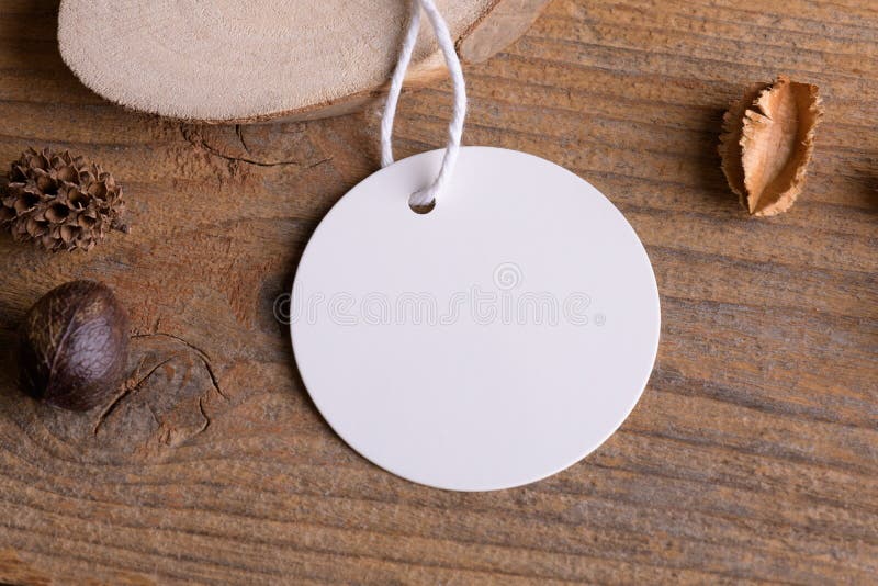 Round white tag mockup on a rustic wooden background with cotton string and boho decoration