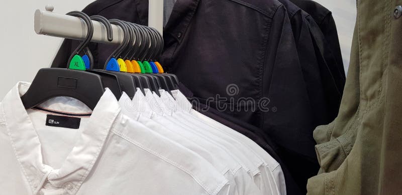 Roupa moderna em uma loja em um gancho Camisas e camisetas do dif imagem de stock Roupa moderna em uma loja em um gancho Camisas e camisetas do dif imagem de stock