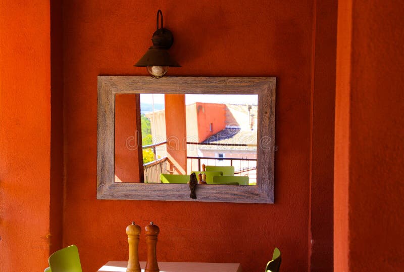 View over isolated table with salt and pepper mill on red wall with mirror showing outside balcony