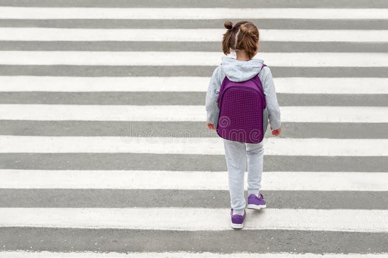 Schoolgirl crossing road on way to school. Zebra traffic walk way in the city. Concept pedestrians passing a crosswalk. Stylish young teen girl walking with backpack. Active child. Top view. Schoolgirl crossing road on way to school. Zebra traffic walk way in the city. Concept pedestrians passing a crosswalk. Stylish young teen girl walking with backpack. Active child. Top view