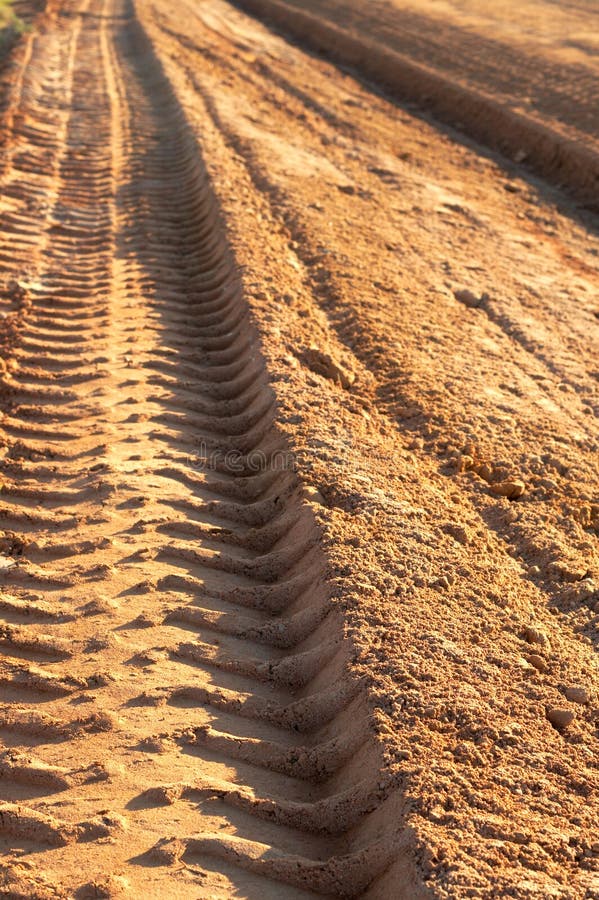 Dusty gravel road with tyre imprints , shot at sunset. Dusty gravel road with tyre imprints , shot at sunset