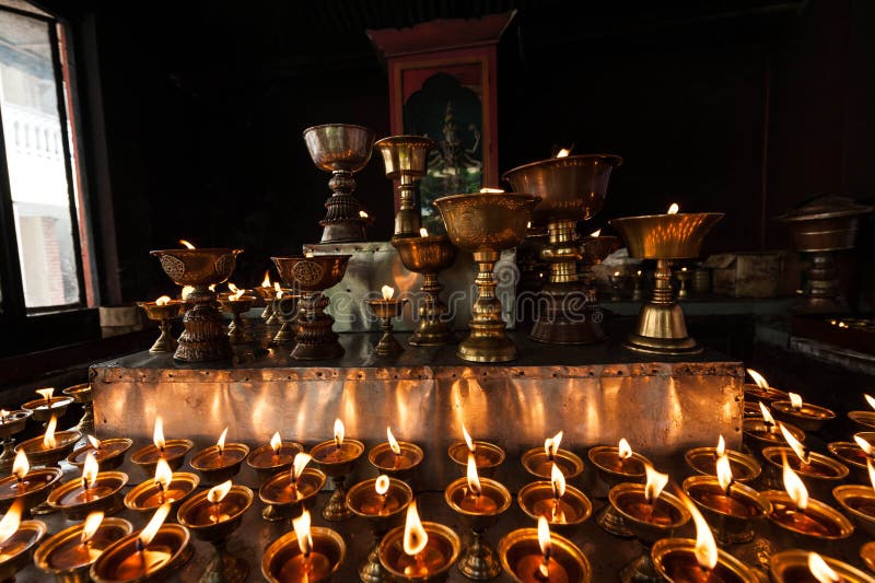 Row of burning butter lamps in a Tibetan Buddhist temple