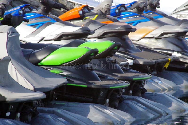 Row of colorful jet skis for rent and parked in a marina.