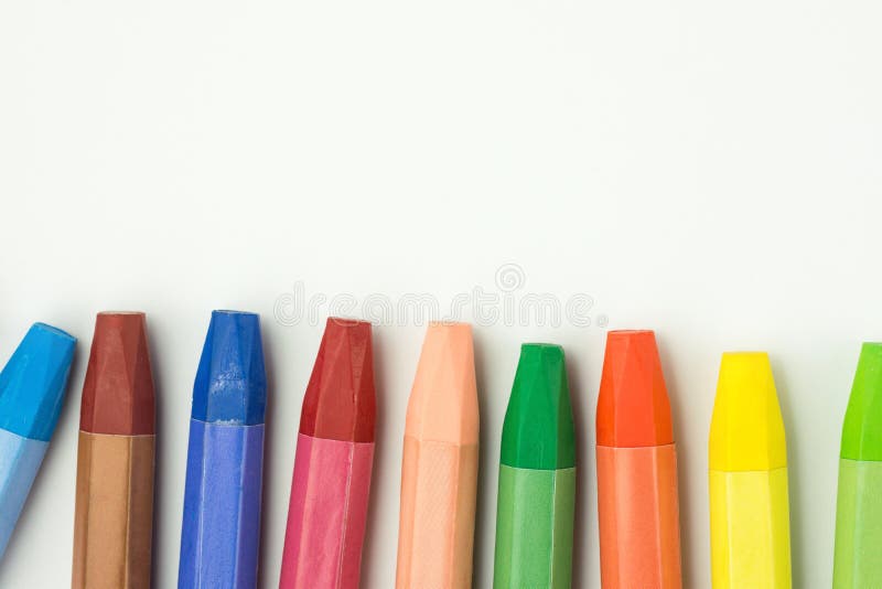 Row of Colorful Multicolored Pastel Wax Crayons on White Paper. Back to School Kids Arts Creativity Drawing Hobby Concept