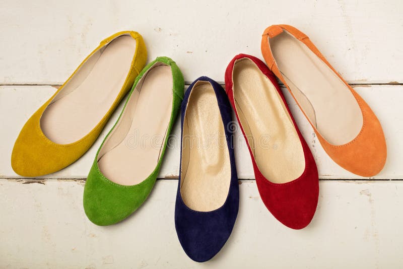 Row of colorful shoes ballerinas on a white wooden background.