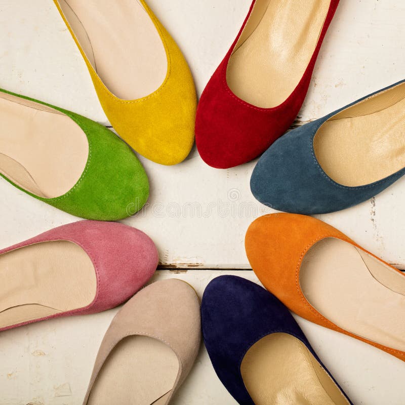 Row of colorful shoes ballerinas on a white wooden background.