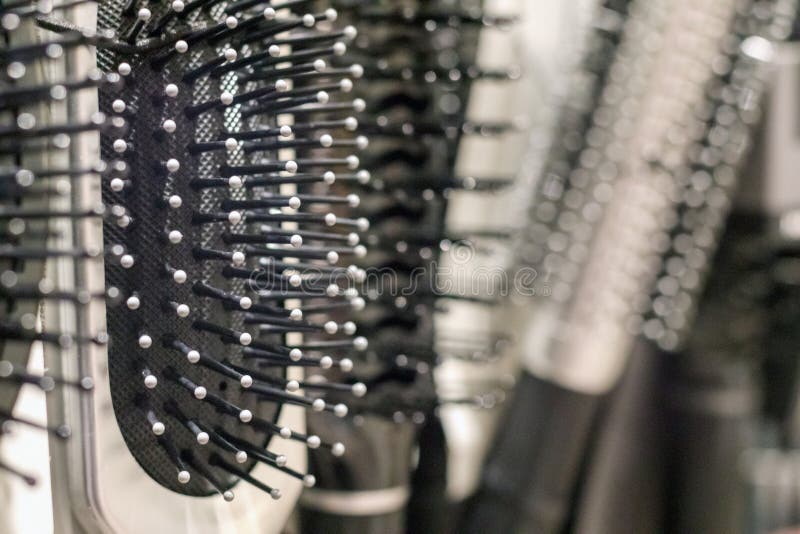 A row of different types of hairbrushes is visible, mostly black, with metal bristles and round tips of various sizes. Types conflict stock images, royalty-free photos and pictures