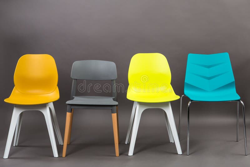 Row of four color plastic chairs isolated on gray background. Furniture series.