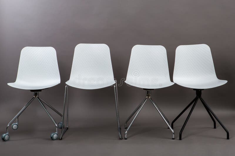 Row of four white plastic chairs isolated on gray background. Furniture series.