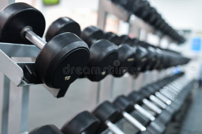 A Rack of Heavy Dumbbells with Weight Labels in Kilograms at the Gym. Weight Training Equipment