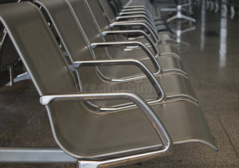 A Row Of Metal Chrome Grey Shiny Seats On The Floor Of Large Tiles