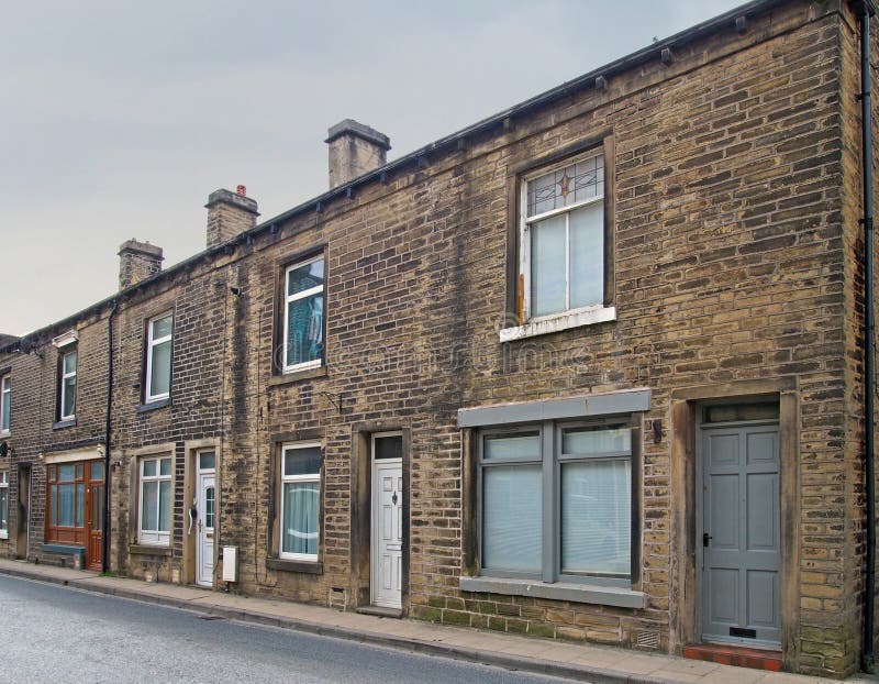 Row of traditional english old working class terraced houses on a street with grey cloudy sky