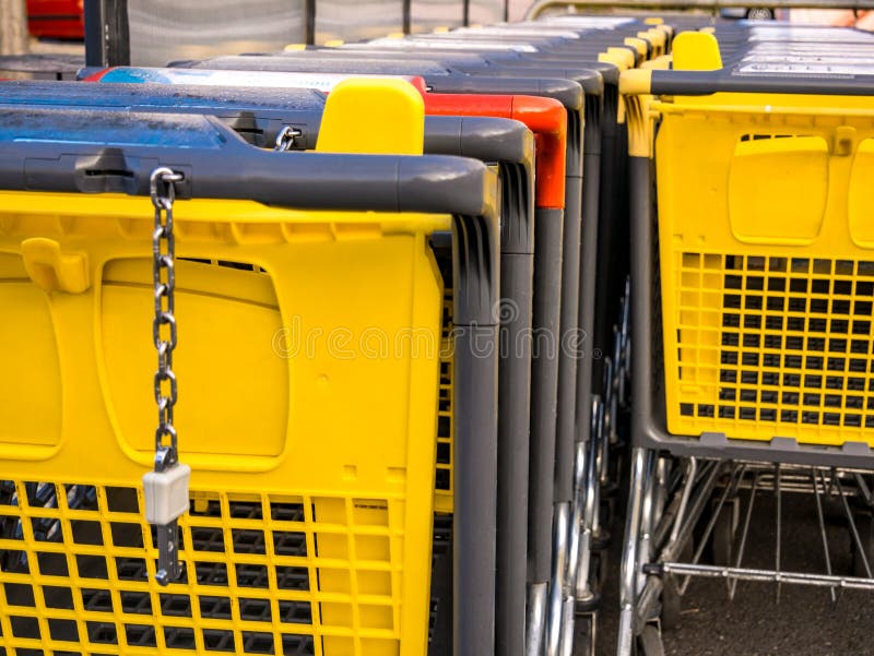 Row of Yellow and One Red Shopping Carts at the Supermarket Stock Photo