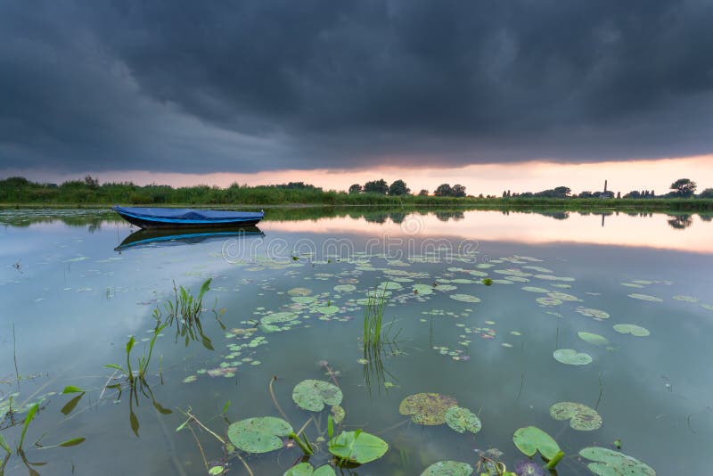 Rowing boat on a small lake during a cloudy sunset.