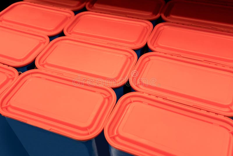 Rows of red plastic lids with blue containers stock images