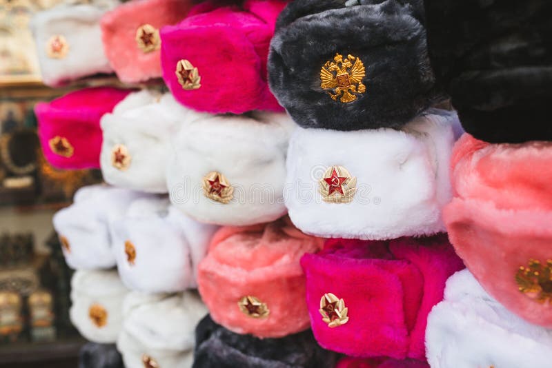 Rows of russian winter hats of different colors with army emblems at the street market iconic popular souvenir from