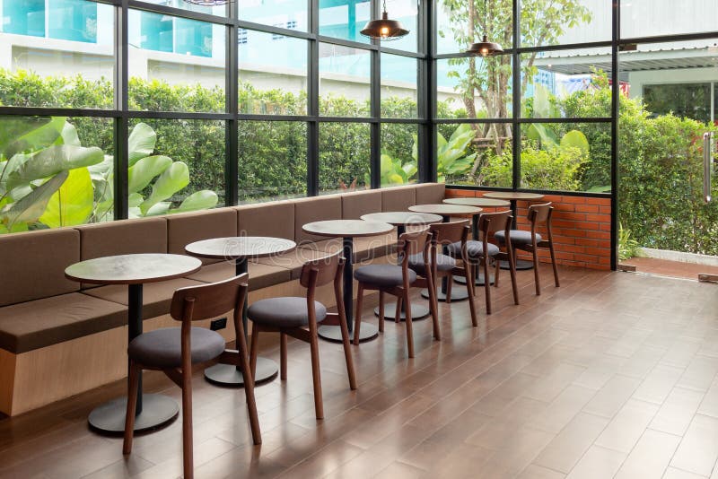 Rows of wooden table and chair inside of glass room with garden royalty free stock photography Rows of wooden table and chair inside of glass room with garden royalty free stock photography