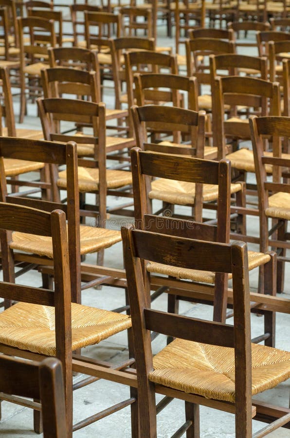 Rows of worn chairs in a church stock image
