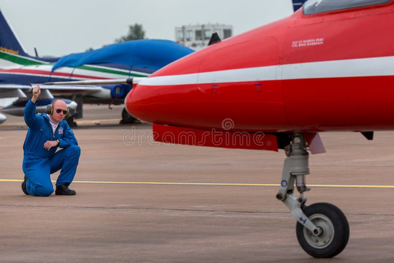 Royal Air Force-het lid van de grondbemanning geeft richtingen aan de loods van aan een Rode Pijlen Britse Ruimtevaarthavik T 1 s royalty-vrije stock foto Royal Air Force-het lid van de grondbemanning geeft richtingen aan de loods van aan een Rode Pijlen Britse Ruimtevaarthavik T 1 s royalty-vrije stock foto