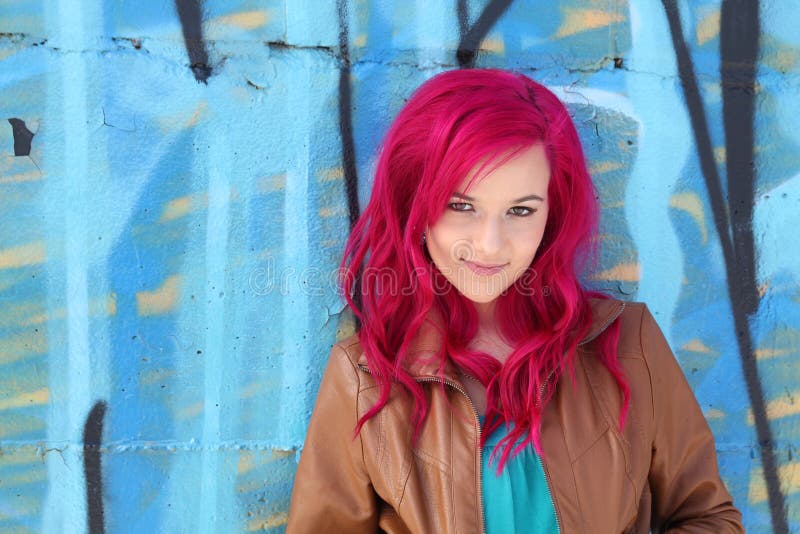 Roze haarmeisje tegen een blauwe muur