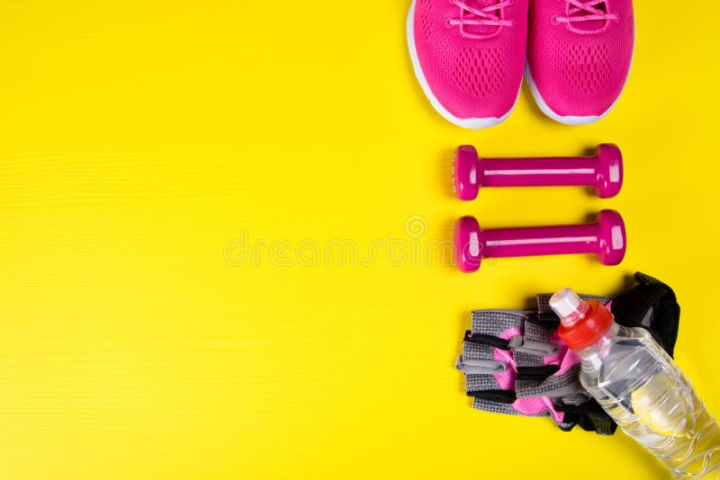 Roze tennisschoenen en toebehoren voor geschiktheid, en een fles water, op een gele achtergrond, met een plaats voor het schrijve stock afbeelding Roze tennisschoenen en toebehoren voor geschiktheid, en een fles water, op een gele achtergrond, met een plaats voor het schrijve stock afbeelding