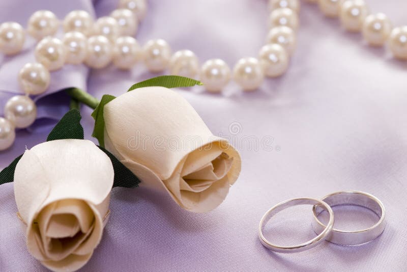 Roses and wedding rings over satin. Roses and wedding rings over satin