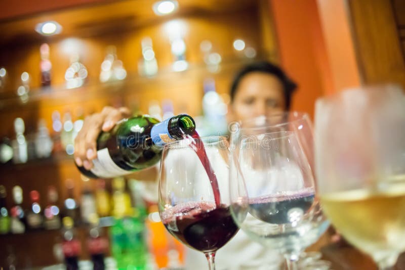 Rozmyty mężczyzna dolewania czerwone wino w szkło z białego wina foregroun fotografia stock