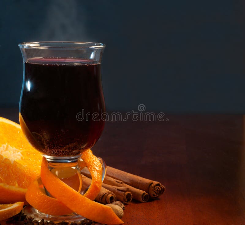 Mulled wine with orange and spices on the table against black background with copy space. Mulled wine with orange and spices on the table against black background with copy space