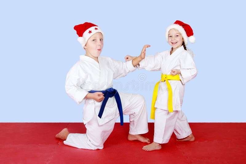 Rozochoceni dzieciaki w nakrętkach Święty Mikołaj robi technika karate zdjęcie royalty free Rozochoceni dzieciaki w nakrętkach Święty Mikołaj robi technika karate zdjęcie royalty free
