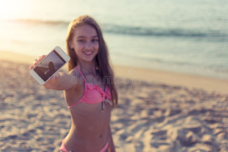 Rozochocona młoda kobieta bierze selfie na piaskowatej plaży z morzem w tle na gorącej letni dzień podróży i turystyki pojęciu obraz stock Rozochocona młoda kobieta bierze selfie na piaskowatej plaży z morzem w tle na gorącej letni dzień podróży i turystyki pojęciu obraz stock