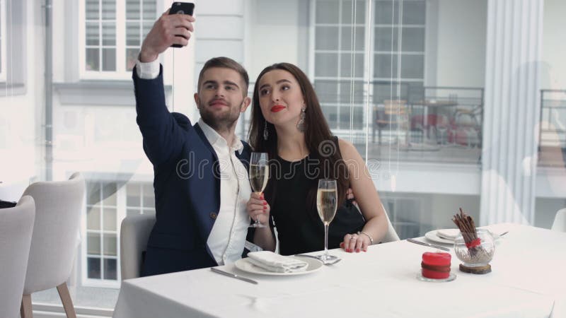 Rozochocona para bierze humorystycznego selfie z smartphone przy restauracją obrazy royalty free Rozochocona para bierze humorystycznego selfie z smartphone przy restauracją obrazy royalty free