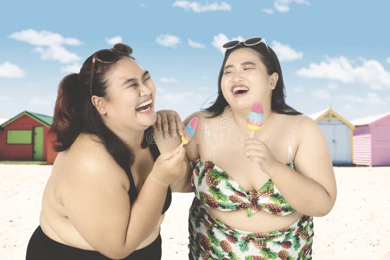 Rozochocone kobiety jedzą lody na plaży obrazy stock Rozochocone kobiety jedzą lody na plaży obrazy stock