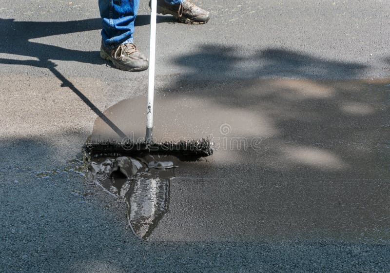 Rozprzestrzeniać asfaltowego sealant na podjeździe