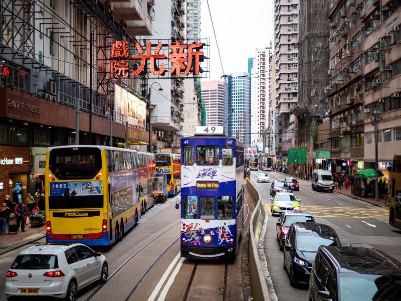 A rua de Bustling, em Hong Kong, com um elétrico e ônibus em meio a prédios altos imagens de stock