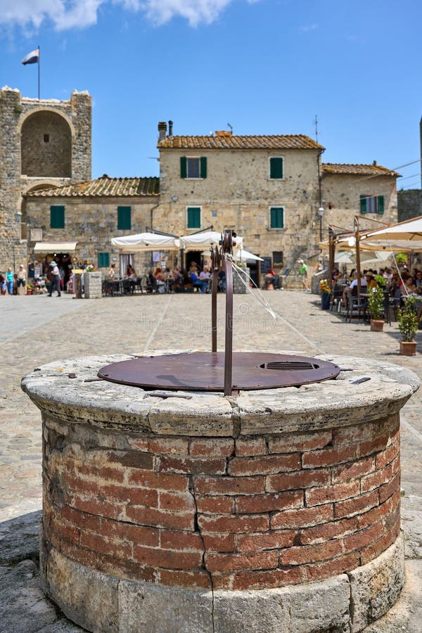 Rua movimentada com um poço de pedra tradicional em monteriggioni itália. foto de stock royalty free