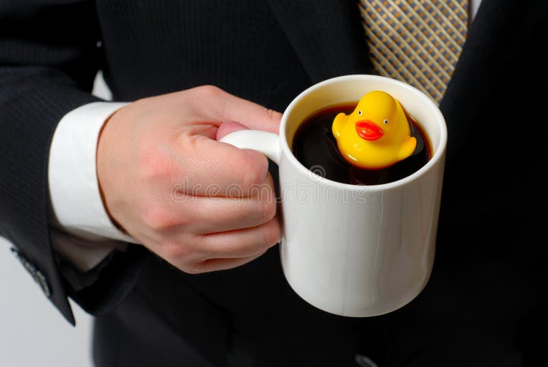 Rubber Ducky in Coffee Cup 2. Yellow rubber ducky floating in a coffee cup being held by a man in a business suit royalty free stock photography Rubber Ducky in Coffee Cup 2. Yellow rubber ducky floating in a coffee cup being held by a man in a business suit royalty free stock photography