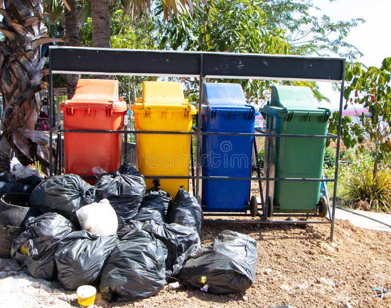 Plastic large trash cans with the lids up and garbage inside against a  brick orange wall. Big green and grey plastic dumpsters on a city street.  Waste Stock Photo - Alamy