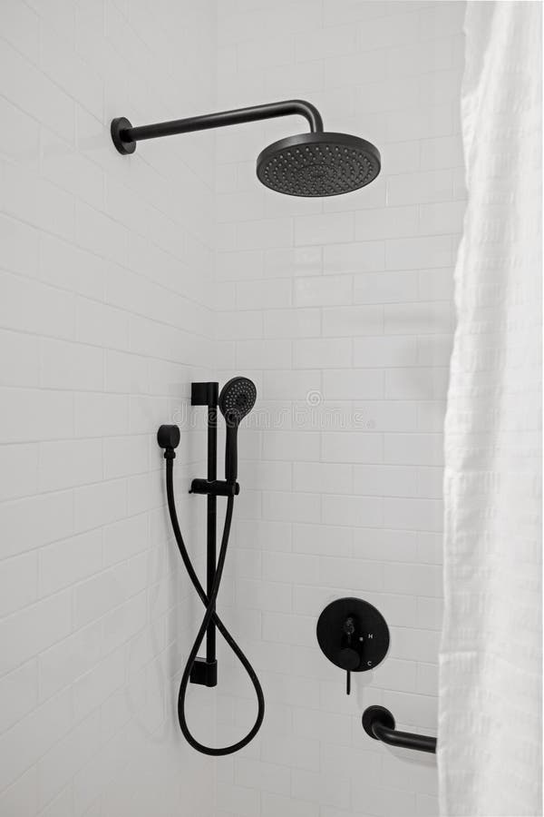 A shower faucet and handheld shower hose mounted on a tiled shower wall. A shower faucet and handheld shower hose mounted on a tiled shower wall.