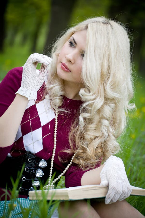 Hermosa joven rubia con libro en un parque de verano fotografía de archivo