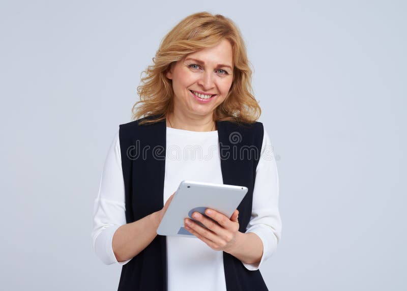Rubio maduro con la PC de la tableta que sonríe en la cámara imagenes de archivo Rubio maduro con la PC de la tableta que sonríe en la cámara imagenes de archivo
