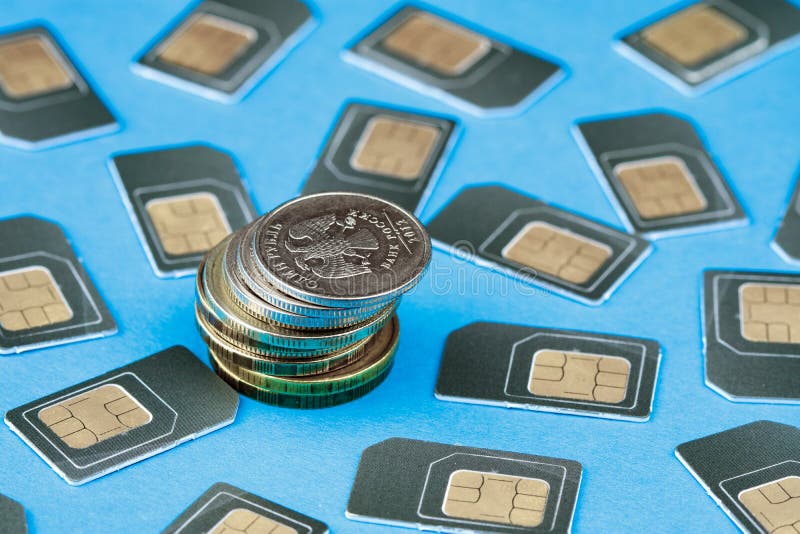 Rublos rusas de monedas apiladas en pilas cerca de las tarjetas grises dispersadas de SIM para su teléfono fotos de archivo Rublos rusas de monedas apiladas en pilas cerca de las tarjetas grises dispersadas de SIM para su teléfono fotos de archivo