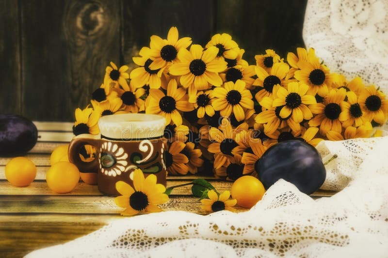 Rudbeckia flowers and a cup of coffee with autumn fruits on the window. Plums and plums on the windowsill.