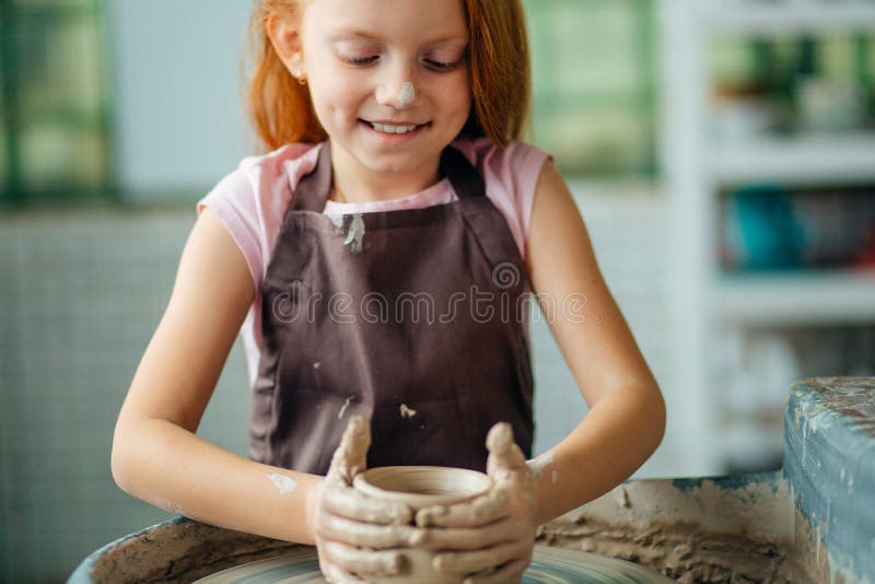 Rudzielec dziecko sculpts od glinianego garnka warsztat na wzorowaniu na garncarki ` s kole obrazy royalty free Rudzielec dziecko sculpts od glinianego garnka warsztat na wzorowaniu na garncarki ` s kole obrazy royalty free