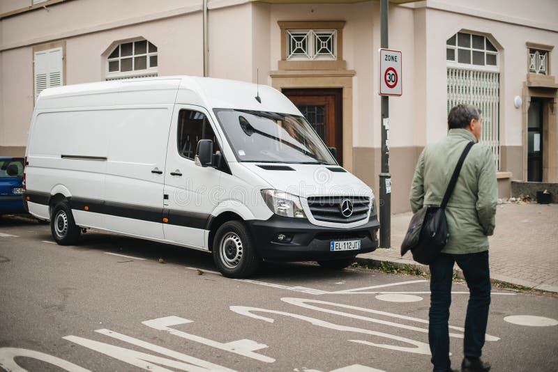 Rue adulte de croisement d'homme devant le fourgon blanc de Mercedes-Benz Sprinter images stock Rue adulte de croisement d'homme devant le fourgon blanc de Mercedes-Benz Sprinter images stock