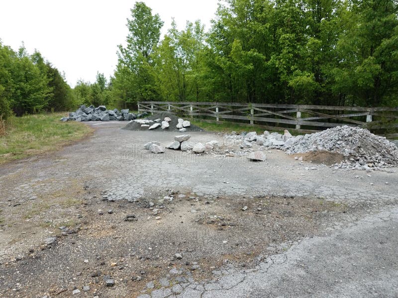 Rue d'asphalte avec piles de roches ou de pierres grises et d'arbres images libres de droits Rue d'asphalte avec piles de roches ou de pierres grises et d'arbres images libres de droits