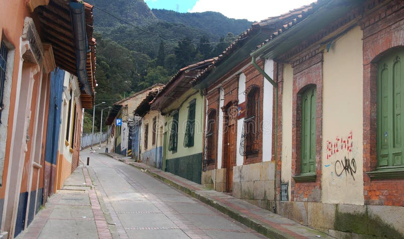 Scenic view of houses lining narrow cobble stoned street in Candelaria district of Bogota with mountains in background, Colombia. Scenic view of houses lining narrow cobble stoned street in Candelaria district of Bogota with mountains in background, Colombia.