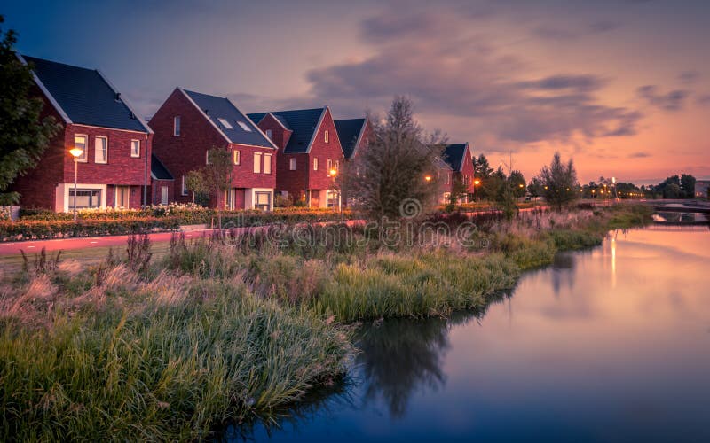 Long exposure night shot of Street with modern ecological middle class family houses with eco friendly river bank in Veenendaal city, Netherlands. Vintage look image. Long exposure night shot of Street with modern ecological middle class family houses with eco friendly river bank in Veenendaal city, Netherlands. Vintage look image