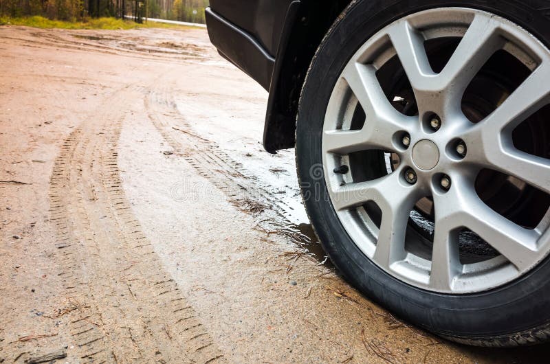 Rueda de coche con el disco de la aleación ligera en la carretera nacional sucia imagen de archivo libre de regalías Rueda de coche con el disco de la aleación ligera en la carretera nacional sucia imagen de archivo libre de regalías