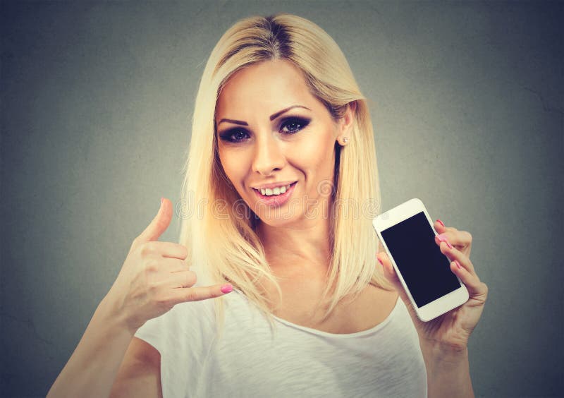 Closeup of a young woman pretty smiling holding phone showing call me sign hand gesture looking at you camera. Closeup of a young woman pretty smiling holding phone showing call me sign hand gesture looking at you camera